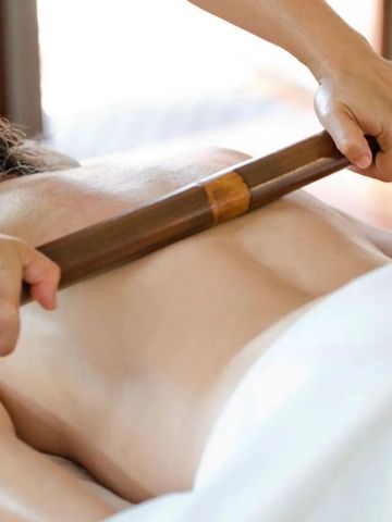 Person erhält eine entspannende Massage mit einem Holzbügel