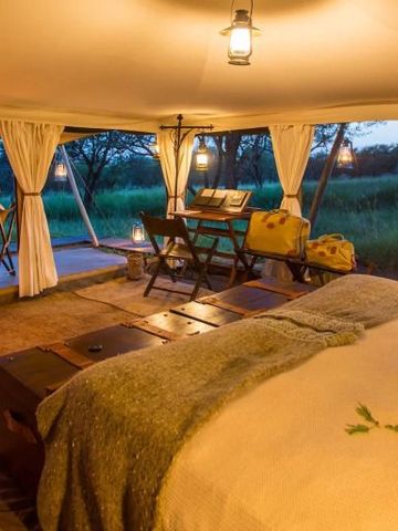 Innenansicht eines Zeltes mit Panoramablick auf die Savanne bei Sonnenuntergang