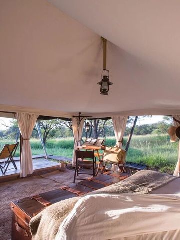 Innenbereich eines Zeltes mit großem Fenster und Aussicht auf grüne Landschaft