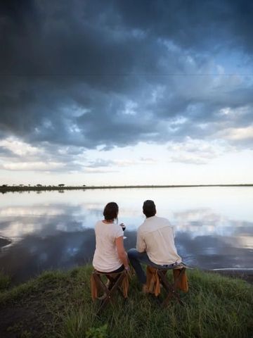 Paar sitzt am Seeufer und genießt die Aussicht unter bewölktem Himmel