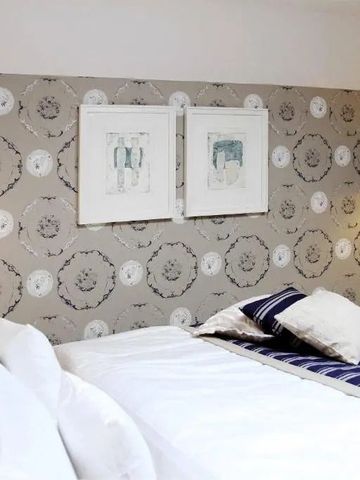 Schlafzimmer mit dekorativer Tapete und stilvollem Kopfteil