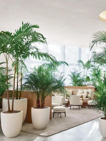 Luxuriöse Lobby mit üppigen Pflanzen. Elegante Sitzbereiche und helle Wandgestaltung.