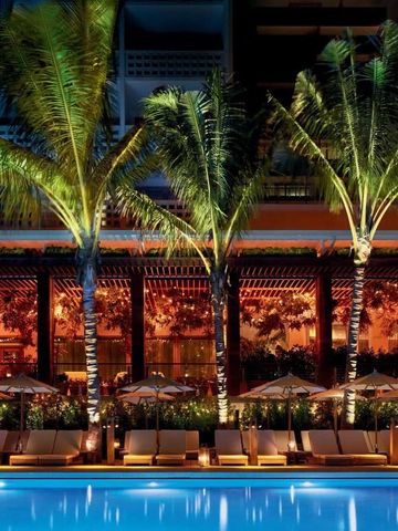 Beleuchteter Außenpoolbereich mit Palmen bei Nacht. Gemütliche Liegen und elegante Atmosphäre.