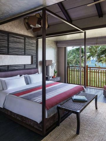 Hotelzimmer mit Himmelbett und Balkon mit Meerblick.