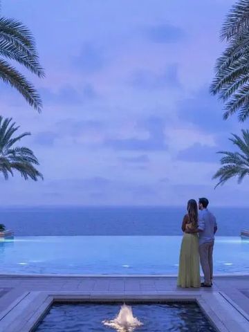 Paar am Infinity Pool bei Sonnenuntergang im Shangri-La Al Husn