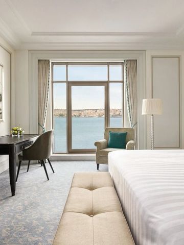 Geräumiges Hotelzimmer mit Fenster und Blick auf das Wasser.