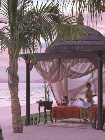 Strandszene mit Pavillon und gemütlicher Entspannung bei Sonnenuntergang