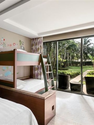 Familienzimmer mit Etagenbett und Gartenblick durch große Fenster.