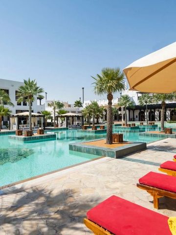 Strahlend blauer Pool umgeben von Palmen und bequemen Liegestühlen.