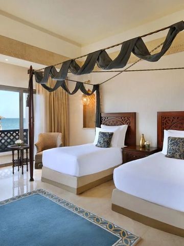 Zimmer mit zwei Himmelbetten und Balkon mit Meerblick.