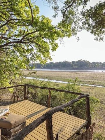 Holzterrasse mit Blick auf Flusslandschaft und üppige Vegetation