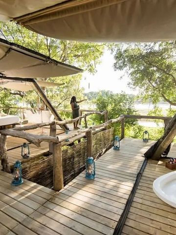 Offene Terrasse mit Blick auf den Fluss. Holzplattform mit Badewanne und Hängematten.