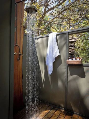 Offene Dusche im Freien mit Handtuch und Naturkulisse.