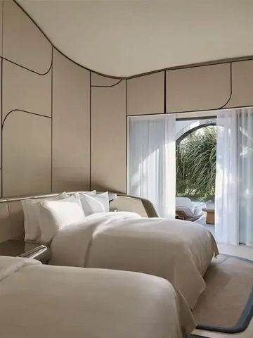 Modernes Schlafzimmer mit zwei Betten und Zugang zu einem privaten Balkon.