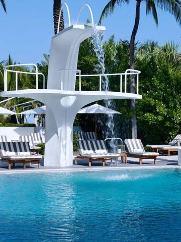 Außenpool mit Wasserfall und Liegestühlen umgeben von Palmen