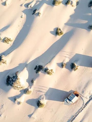 Luftaufnahme von zwei einsamen Hütten inmitten einer Dünenlandschaft