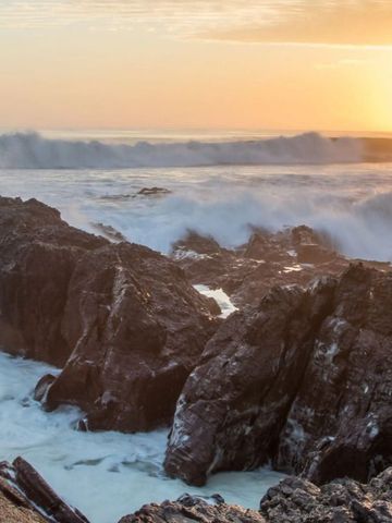 Dramatische Brandung an felsiger Küste im Sonnenuntergang