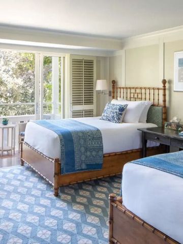 Helles Hotelzimmer mit zwei Betten und großen Fenstern mit Gartenblick