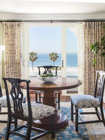 Essbereich mit Tisch und Stühlen vor großen Fenstern mit Meerblick