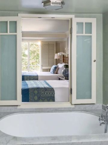 Badezimmer mit Wanne und Durchsicht auf ein gemütliches Schlafzimmer