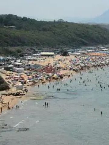 Belebter Strand an der sizilianischen Küste mit zahlreichen Badegästen.