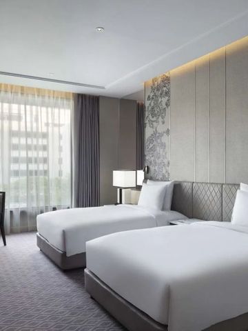 Modernes Doppelzimmer mit zwei Einzelbetten und stilvollen Tapeten.