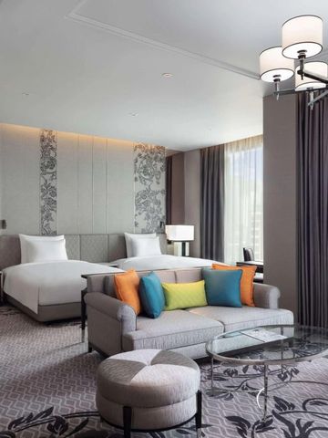 Suite mit gemütlichem Sofa, dekorativen Kissen und zwei Betten.