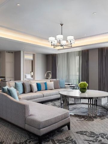 Großzügiges Wohnzimmer in Suite mit eleganter Einrichtung und Glasluster.