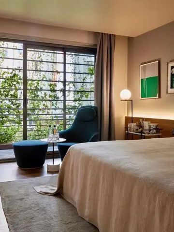 Gemütliches Schlafzimmer mit großem Bett und Balkon mit Blick auf Grünelemente