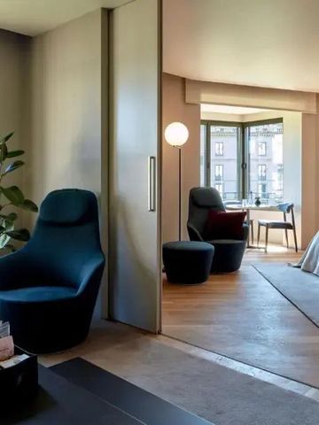 Modernes Hotelzimmer mit gemütlicher Sitzecke und großem Fenster mit Stadtblick