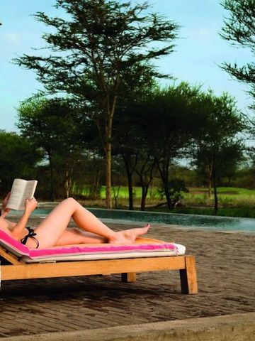 Frau entspannt auf Sonnenliege mit Blick auf die Natur am Pool