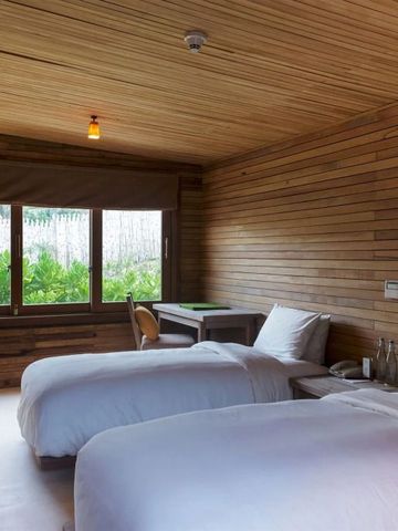 Zweibettzimmer mit Holzwänden und großem Fenster mit Gartenblick