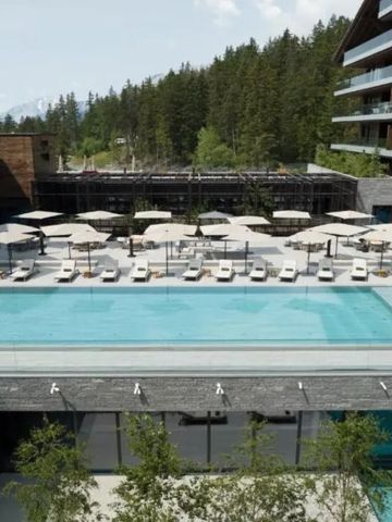 Infinity-Pool im Außenbereich mit Sonnenliegen und Blick auf die Berge