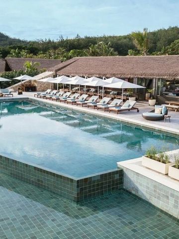Infinity-Pool am Hotel mit Liegestühlen und tropischer Vegetation