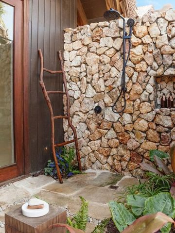 Außendusche in einer rustikalen Umgebung mit Steinwand und Holzleiter.