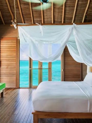 Helles Schlafzimmer mit Moskitonetz und Blick auf das Meer