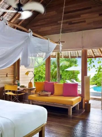 Offenes Schlafzimmer mit Blick auf tropische Vegetation und Pool