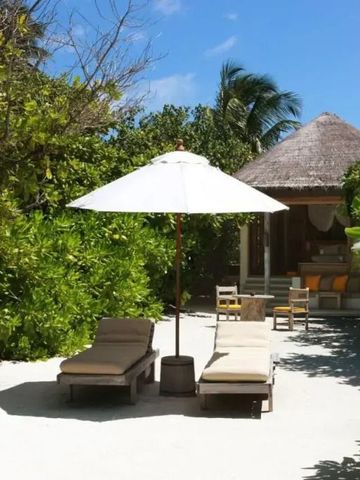 Sonnenterrasse mit Liegestühlen und Sonnenschirm im tropischen Garten
