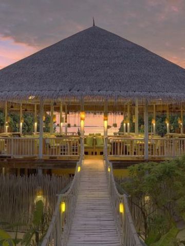 Exotisches Restaurant im Freien mit Strohdach bei Sonnenuntergang