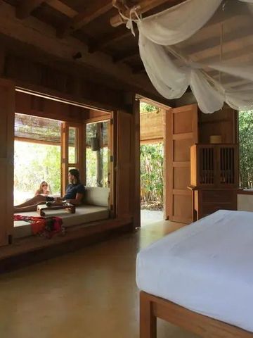 Offenes Schlafzimmer mit Ausblick ins Grüne und gemütlicher Sitzecke.