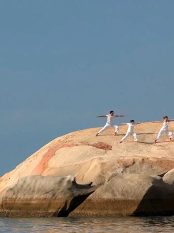 Menschen praktizieren Yoga auf den Felsen am Meeresufer.