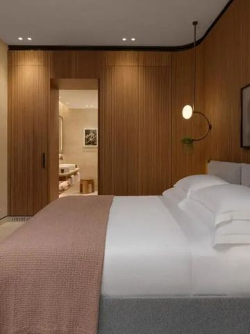 Modernes Hotelzimmer mit Holzwänden, gemütlichem Bett und direktem Badzugang