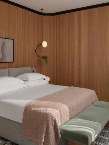 Gemütliches Hotelzimmer mit Holzwänden, komfortablem Doppelbett und Sitzbank