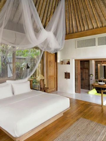 Geräumiges Schlafzimmer mit Baldachin und Holzböden in tropischer Umgebung