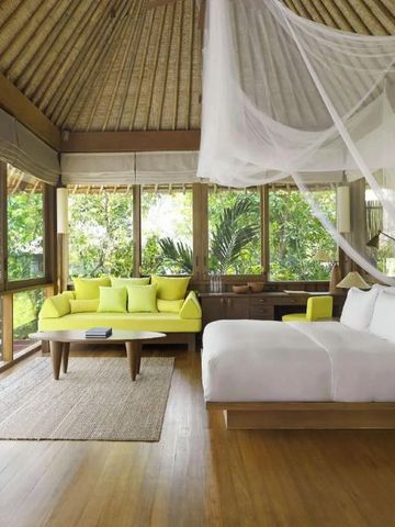 Schlafzimmer mit Baldachin und Sitzecke in tropischer Umgebung