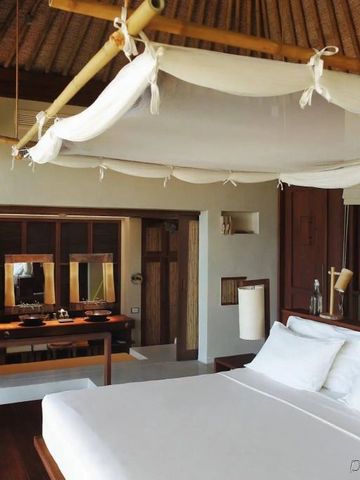 Helles Schlafzimmer mit traditionellem Dach und moderner Einrichtung bei Six Senses Samui