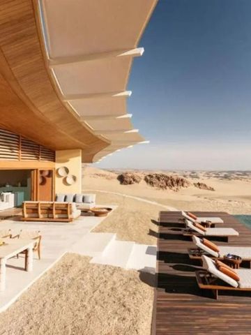 Sonnendeck und Infinity-Pool in Wüstenlandschaft mit stilvollem Schattendach.