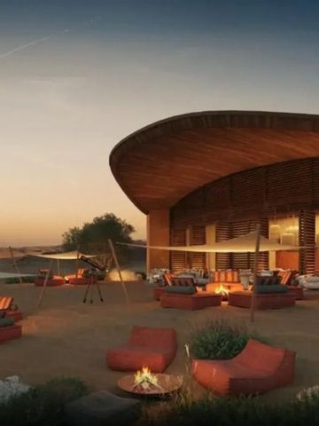 Abendstimmung mit beleuchteten Sitzbereichen und Lagerfeuer vor moderner Architektur.