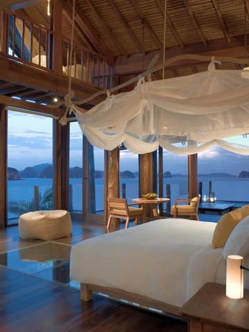 Luxuriöses Schlafzimmer mit Himmelbett und Blick auf das Meer bei Sonnenuntergang