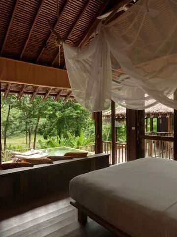 Schlafzimmer mit Himmelbett und Ausblick auf dichte tropische Gärten